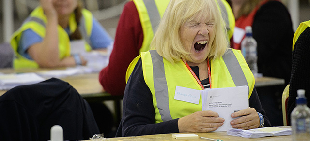 A woman shows signs of fatigue as she counts ballot cards at the Royal Highland Centre counting hall in Edinburgh, Scotland on September 19, 2014, after ballot counting got underway in the referendum on Scottish independence. In counting centres, jam-packed pubs and living rooms across Scotland, voters were nervously waiting for the results of their historic vote on whether or not to leave the United Kingdom. AFP PHOTO/LEON NEAL (Photo credit should read LEON NEAL/AFP/Getty Images)