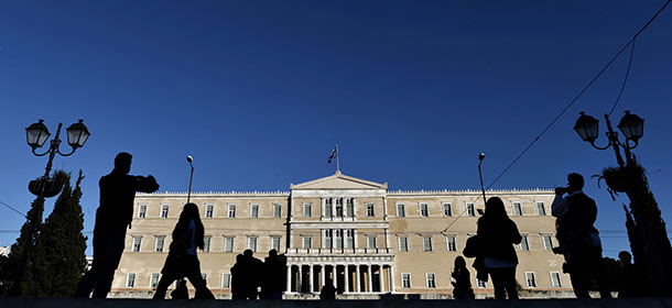 People walk past the Greek parliament in Athens on December 17, 2014. Greece stood a step away from early elections that could repudiate its international bailout and rekindle a eurozone crisis after lawmakers failed to elect a president. The government candidate, EU Environment Commissioner Stavros Dimas, fell 32 votes short of the required 200 votes in the second attempt by lawmakers to elect a president, meaning a third and final vote will be held on December 29. AFP PHOTO / ARIS MESSINIS (Photo credit should read ARIS MESSINIS/AFP/Getty Images)
