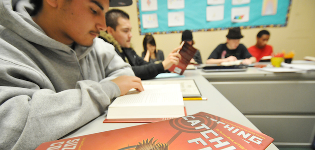 In this photo Wednesday, March 21, 2012, Enrique Aguilar, 16, follows along during an in-class reading of "Catching Fire," the second book in "The Hunger Games" series by Suzanne Collins at the Option for Youth public charter school campus in Victorville, Calif. Students has been actively engaged since teacher Martin Votruba chose to plan his lessons around the popular contemporary fiction. (AP Photo/The Victor Valley Daily Press, David Pardo)