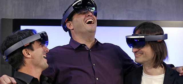 Microsoft's Joe Belfiore, left, Terry Myerson and Alex Kipman playfully pose for a photo as they wear "Hololens" devices following an event demonstrating new features of the operating system Windows at the company's headquarters Wednesday, Jan. 21, 2015, in Redmond, Wash. Executives demonstrated how they said the new Windows is designed to provide a more consistent experience and a common platform for software apps on different devices, from personal computers to tablets, smartphones and even the company's Xbox gaming console. (AP Photo/Elaine Thompson)