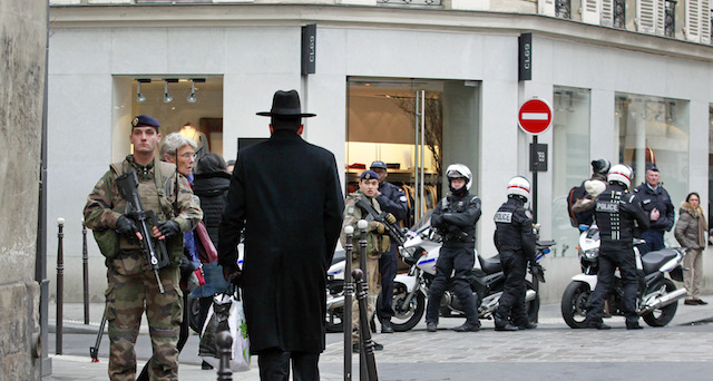 Police officers and French army soldiers patrol Rue des Rosiers street, in the heart of Paris Jewish quarter, in Paris, Monday Jan. 12, 2015. France on Monday ordered 10,000 troops into the streets to protect sensitive sites after three days of bloodshed and terror, amid the hunt for accomplices to the attacks that left 17 people and the three gunmen dead. (AP Photo/Remy de la Mauviniere)