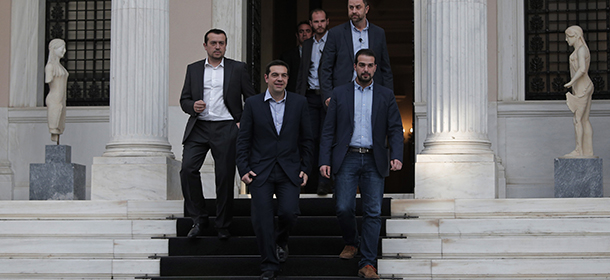 Greece's Prime Minister Alexis Tsipras, center, accompanied by close associates, walks out of his office on his way to the Presidential Palace to attend his government's swearing in ceremony in central Athens, Tuesday, Jan. 27, 2015. Tsipras picked an outspoken bailout critic, Yanis Varoufakis, as his new finance minister Tuesday, signaling his revolve to take a tough line with eurozone lenders in an effort to write off a massive chunk rescue debt. (AP Photo/Lefteris Pitarakis)
