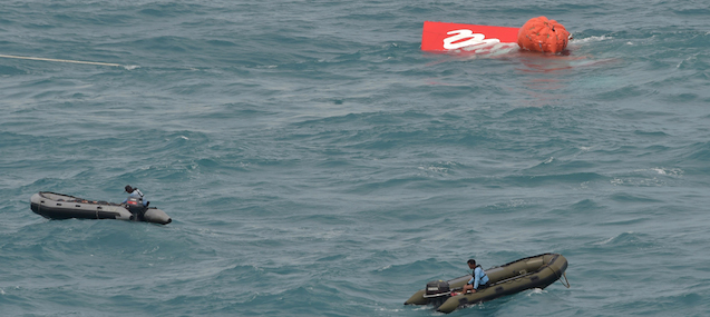 Part of the tail of AirAsia flight QZ8501 floats on the water's surface as Indonesian Navy divers conduct search operations for black boxes of the aircraft in the Java sea on January 10, 2015. Indonesian military divers chased on January 10 faint signals believed to be from the black box data recorders of an AirAsia plane that crashed in stormy weather, killing all 162 people on board. AFP PHOTO / POOL / ADEK BERRY