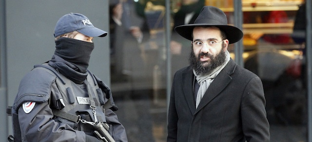 A police officer talks a Jew outside the kosher grocery where Amedy Coulibaly killed four people in a terror attack, in Paris, Tuesday Jan.20, 2015. New York mayor Bill de Blasio is expected to pay respect to the victims at the killing sites later today. Brothers Said and Cherif Kouachi and their friend, Amedy Coulibaly, killed 17 people at the satirical newspaper Charlie Hebdo, a kosher grocery and elsewhere last week.(AP Photo/Francois Mori)