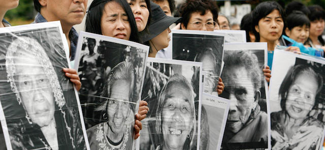 Tokyo, JAPAN: Japanese women hold portraits of Chinese, Philippine, South Korean and Taiwanese former comfort women who were sex slaves for Japanese soldiers during World War II, at a protest held in front of the Japanese parliament in Tokyo, 14 June 2007. About 150 people took part in the protest demanding compensation by the Japanese government. AFP PHOTO/Toru YAMANAKA (Photo credit should read TORU YAMANAKA/AFP/Getty Images)