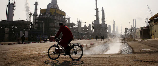 An Iranian oil worker rides his bicycle at the Tehran's oil refinery south of the capital Tehran, Iran, Monday, Dec. 22, 2014. (AP Photo/Vahid Salemi)