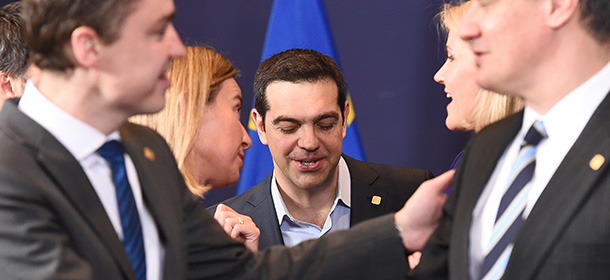Greek Prime Minister Alexis Tsipras (C) speaks with fellow delegates during a family photo at an European Council leaders summit in Brussels on February 12, 2015. AFP PHOTO / EMMANUEL DUNAND (Photo credit should read EMMANUEL DUNAND/AFP/Getty Images)