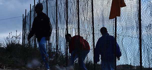 LAMPEDUSA, ITALY - FEBRUARY 18: Migrants go through a hole of the external fence of the Temporary Permanence Centre (CPT) on February 18, 2015 in Lampedusa, Italy. Hundreds of migrants have recently arrived in Lampedusa fleeing the attacks by ISIS in Libya. The Temporary Permanence Centre' (CPT) of Lampedusa, which was designed to accommodate 250, currently holds about 1,200 migrants following Sunday's rescue of 2,000 in the Mediterranean Sea between the island of Lampedusa and the Libyan coast (Photo by Tullio M. Puglia/Getty Images)
