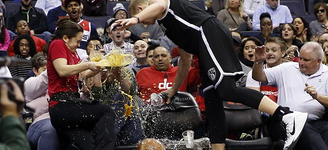 Waitress Deila Barr looses a tray of beers as Brooklyn Nets center Mason Plumlee (1) runs into her chasing the ball in the first half of an NBA basketball game against the Washington Wizards, Saturday, Feb. 7, 2015, in Washington. (AP Photo/Alex Brandon)