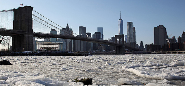 Ice forms on the Brooklyn waterfront in New York on Sunday, Feb. 15, 2015. An extremely cold air mass is moving into the region on Sunday night. The Brooklyn Bridge and One World Trade Center appear in the background. (AP Photo/Peter Morgan)