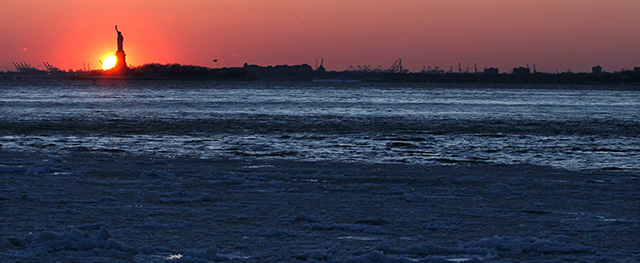 Ice forms on the Brooklyn waterfront as the sun sets behind the Statue of Liberty in New York on Sunday, Feb. 15, 2015. An extremely cold air mass is moving into the region on Sunday night. (AP Photo/Peter Morgan)