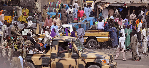 FILE -In this file photo taken Tuesday, Jan. 27, 2015, Nigerian Soldiers, left, pass by on the back of a armed truck as they patrol at a local market after recent violence in surrounding areas at Maiduguri, Nigeria. Nigerian and Chadian jets are bombing Boko Haram out of a slew of northeastern Nigerian towns and villages, witnesses and officials said Wednesday, Feb. 4, 2015, of the first major offensive against the Islamic extremists whose insurgency was spreading across borders. (AP Photo/Jossy Ola, File)