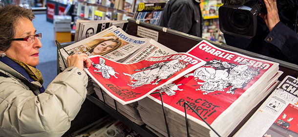 A woman picks up the latest edition of French satirical weekly newspaper Charlie Hebdo at a newsstand on February 25, 2015 in Lille. More than a month after jihadist gunmen massacred much of the Charlie Hebdo editorial staff, the magazine is back at work with another savage swipe at its favourite enemies. The team has lain low since rushing out a "survivors' issue" a week after the jihadist attack that killed 12 people, including five of France's best-loved cartoonists, on January 7. AFP PHOTO /PHILIPPE HUGUEN (Photo credit should read PHILIPPE HUGUEN/AFP/Getty Images)