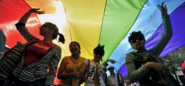People walk under a huge rainbow flag during a rally celebrating the validity of the new law on homosexual marriage --the first of its kind in Latin America which also considers the possibility of adoption, on March 14, 2010 in Mexico City. AFP PHOTO/Alfredo Estrella (Photo credit should read ALFREDO ESTRELLA/AFP/Getty Images)
