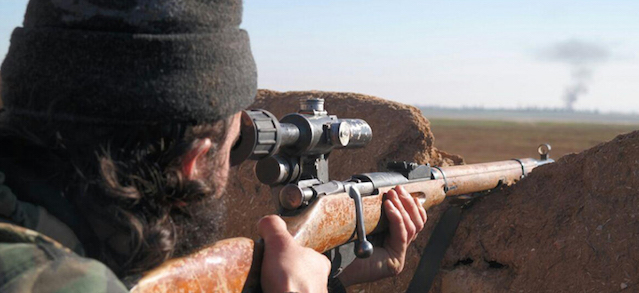 In this image posted on a militant social media account by the Al-Baraka division of the Islamic State group on Tuesday, Feb. 24, 2015, a militant fighter aims a sniper rifle during during fighting in Tal Tamr, Hassakeh province, Syria. Fierce fighting between Kurdish and Christian militiamen and Islamic State militants is continuing on Wednesday, Feb. 25 in northeastern Syria where the extremist group recently abducted at least 70 Christians. (AP Photo via militant social media account)