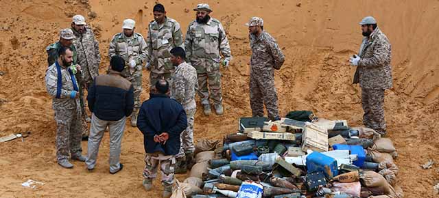 Members of the Military College of Engineering from Misrata stand next to unexploded munitions, found around the Libyan international airport after weeks of fighting, before their destruction on February 10, 2015 in Tripoli. UNSMIL, the United Nations Support Mission in Libya, said in a statement on February 9, 2015 that meetings will be held in both Libya itself and in the Swiss city of Geneva on the future of the troubled North African country. AFP PHOTO/ MAHMUD TURKIA (Photo credit should read MAHMUD TURKIA/AFP/Getty Images)