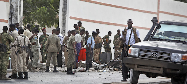 Somali soldiers gather near the destroyed gate of the SYL hotel following a suicide car bomb attack in Mogadishu, Somalia, Thursday, Jan. 22, 2015. A suicide car bomber blew himself up at the gate of the hotel which was being used by a delegation of Turkish officials, killing three Somalis and shattering windows, and coming one day before Turkish President Recep Tayyip Erdogan was due to arrive in the Somali capital. (AP Photo/Farah Abdi Warsameh)