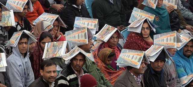 Indian spectators cover themselves with information booklets as it rains during the nation's Republic Day parade on Rajpath in New Delhi on January 26, 2015. Rain failed to dampen spirits at India's Republic Day parade January 26 as Barack Obama became the first US president to attend the spectacular military and cultural display in a sign of the nations' growing closeness. AFP PHOTO/ PRAKASH SINGH (Photo credit should read PRAKASH SINGH/AFP/Getty Images)