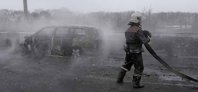 A fireman attends to a car destroyed by a rocket during recent shelling in Donetsk, Ukraine, Monday, Feb. 9, 2015. An armed conflict between Russia-backed separatists and Ukraine government forces has killed more than 5,300 people and displaced more than a million people in eastern Ukraine. (AP Photo/Petr David Josek)