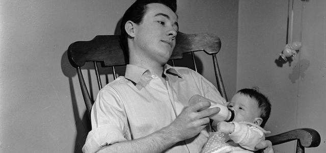circa 1950: A contented father feeds his daughter from a bottle. (Photo by Three Lions/Getty Images)