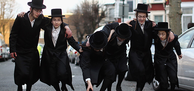 LONDON, ENGLAND - MARCH 05: A group of Orthodox Jewish boys dance in the street before going into the home of a local businessmen while collecting money for their school during the Jewish holiday of Purim on March 5, 2015 in London, England. The annual Purim holiday is celebrated by Jewish communities around the world with parades and costume parties. The Biblical Book of Esther recorded the deliverance of the Jewish people from a plot to exterminate them in the ancient Persian empire 2,500 years ago and continues to be celebrated today. (Photo by Dan Kitwood/Getty Images)