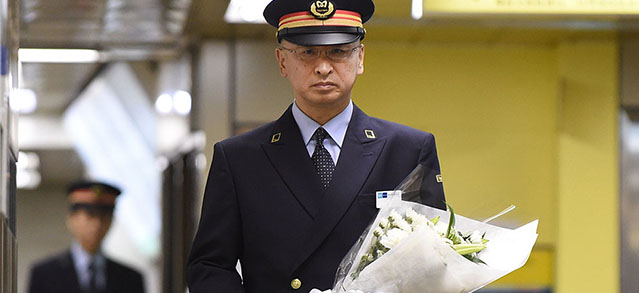 Station master Mitsuaki Ota, carrying a bouquet of flowers, walks toward an altar for the victims of the 1995 deadly nerve-gas attack in Tokyo on March 20, 2015. Japan marked the 20th anniversary of the sarin nerve gas attack against Tokyo subways that killed 13 people and injured 6,000. AFP PHOTO / Toru YAMANAKA (Photo credit should read TORU YAMANAKA/AFP/Getty Images)