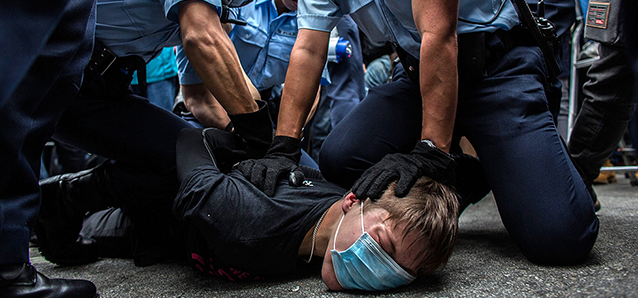 HONG KONG - MARCH 01: Police hold down a protester in Yuen Long during a rally against parallel-goods trading on March 1, 2015 in Hong Kong, Hong Kong. Protestors say the growing number of mainland parallel-goods traders has impacted their daily lives. (Photo by Lam Yik Fei/Getty Images)