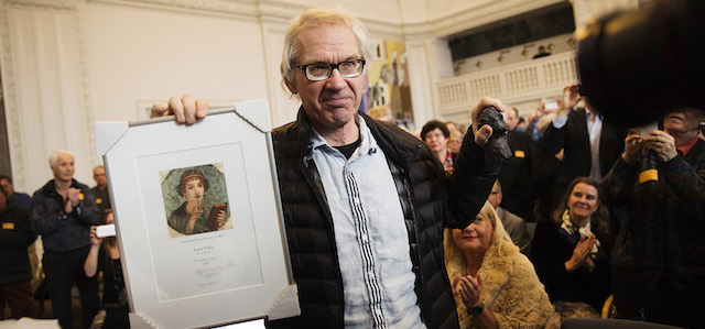 The Swedish cartoonist, Lars Vilks, holds up his Danish Printing Society's Sappho Prize, Saturday March 14, 2015, which he received for his effort for freedom of speech at an meeting in the Danish Parliament at Christiansborg Castle, Copenhagen. (AP Photo/Polfoto, Carsten Bundgaard) DENMARK OUT