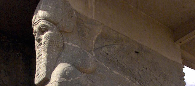 MOSUL, IRAQ: An Iraqi worker stands 21 April 2001 next to the ancient statue of a winged bull with a human face, an indication of strength in the Assyrian civilization, at the archaeological site of Nimrud, south of Mosul in northern Iraq. Nimrud was built in the 13th century B.C. during Mesopotamia's Assyrian era and excavations, carried on since the mid-19th century, have revealed remarkable finds. AFP PHOTO/Karim SAHIB (Photo credit should read KARIM SAHIB/AFP/Getty Images)