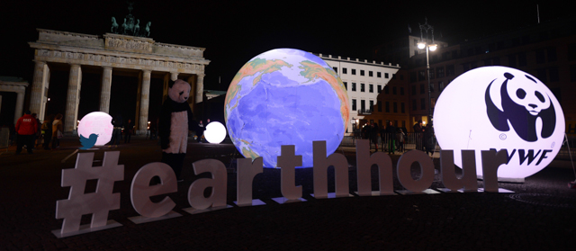A WWF activist dressed as a panda bear stands next to an illuminated globe in front of the Brandenburger Gate in Berlin during the the global climate change awareness campaign "Earth Hour" on March 28, 2015. Millions are expected to take part around the world in the annual event organised by environment conservation group WWF, with hundreds of well-known sights including the Eiffel Tower in Paris and the Seattle Space Needle set to plunge into darkness for an hour to highlight the plight of the planet. AFP PHOTO / JOHN MACDOUGALL (Photo credit should read JOHN MACDOUGALL/AFP/Getty Images)