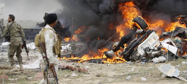 Shi'ite fighters known as Hashid Shaabi look at smoke from an explosives-laden military vehicle driven by an Islamic State suicide bomber which exploded during an attack on the southern edge of Tikrit March 12, 2015. Iraqi security forces and mainly Shi'ite militia exchanged fire sporadically with Islamic State fighters in Tikrit on Thursday, a day after they pushed into Saddam Hussein's home city in their biggest offensive yet against the militants. A Reuters photographer saw one car bomb explode on the southern edge of the city, and security officials say Islamic State fighters have booby-trapped abandoned buildings. REUTERS/Thaier Al-Sudani (IRAQ - Tags: POLITICS CIVIL UNREST CONFLICT MILITARY)