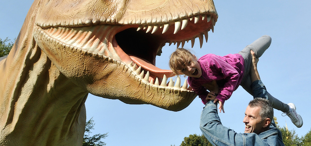 Un uomo prende in braccio una bimba vicino alla riproduzione di un dinosauro del "Mondo dei dinosauri", una mostra tenuta a Kievi in Ucraina nel 2010 (SERGEI SUPINSKY/AFP/Getty Images)