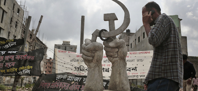 In this Monday, April 20, 2015 photo, a Bangladeshi man walks near a monument erected in memory of the victims of Rana Plaza building collapse, the worst in the history of the garment industry in Savar, near Dhaka, Bangladesh. Human Rights Watch has criticized the Bangladeshi government for failing to protect workers, saying not enough is being done to eliminate assault, intimidation and other abuses still common in the garment industry. Bangladesh suffered its worst industrial disaster when Rana Plaza, an illegally built, multistoried building located outside of Dhaka, Bangladesh's capital, collapsed in 2013 killing 1,127 people and injuring about 2,500. (AP Photo/A.M. Ahad)