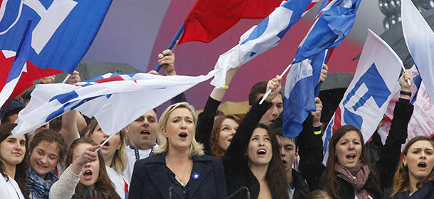 France's far-right National Front candidate leader Marine Le Pen, center left, with supporters, sing French national anthem, during a traditional May Day march in Paris, Thursday May 1, 2014. Thousands of people have joined French far-right leader Marine Le Pen in her party's annual march, their sights set on European elections this month after rousing victories in local voting. Le Pen, who has taken her party from pariah status to mainstream, laid a wreath Thursday at the statue of Joan of Arc, the National Front's patron saint, before addressing a crowd gathered outside the Paris Opera. She condemned the euro and the European Union, but urged followers to vote in European parliamentary elections. Nationalist ideas are making inroads among European voters disillusioned by Europe's economic woes, and could influence May 22-25 voting for a new European Parliament. Le Pen wants to capitalize on recent victories in municipal elections that gave her party control of 11 towns. (AP Photo/Jacques Brinon)