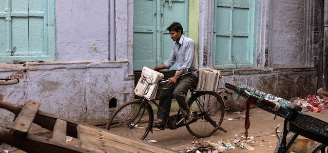 An Indian delivery man carries bundles of newspapers on his bicycle along a back street in New Delhi on April 11, 2015. AFP PHOTO / ALEX OGLE (Photo credit should read Alex Ogle/AFP/Getty Images)