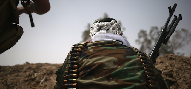EBRAHIM BEN ALI, IRAQ - APRIL 11: A volunteer from the Shia Badr Brigade peers over a berm towards ISIS fighters on the frontline on April 11, 2015 in Ebrahim Ben Ali, in Anbar Province, Iraq. Shia militia and Iraqi government troops are preparing for an assault on ISIS forces in Anbar, much of which was captured by ISIS forces last year. Anbar Province was the site of the some of the fiercest fighting between U.S. and insurgent forces before American troops withdrew in 2010. (Photo by John Moore/Getty Images)