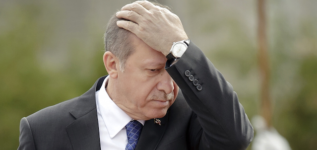 Turkish President Recep Tayyip Erdogan touches his forehead while walking by an honor guard at the Cotroceni presidential palace in Bucharest, Romania, Wednesday, April 1, 2015. Two members of a banned leftist group and a prosecutor they held hostage inside a courthouse in Istanbul died Tuesday after a shootout between the hostage takers and police, officials said. Erdogan is on an official visit to Romania (AP Photo/Vadim Ghirda)