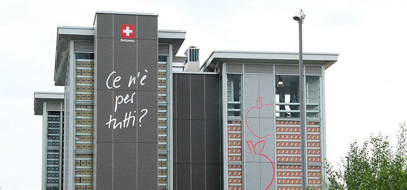 Le quattro torri del padiglione della Svizzera, con la scritta "Ce n'è per tutti?" (Marta Cantoni/Il Post)