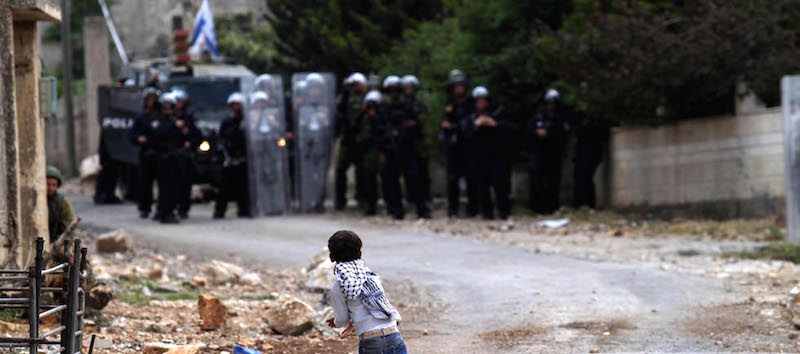 Un bambino palestinese tira una pietra contro i soldati israeliani nel villaggio di Kfar Qaddum, in Cisgiordania (Nedal Eshtayah/APA Images/ZUMA Wire)