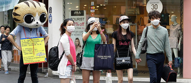 Alcune persone con le mascherine per ridurre il rischio di contagio da MERS in una delle aree commerciali di Seul, Corea del Sud (AP Photo/Ahn Young-joon)