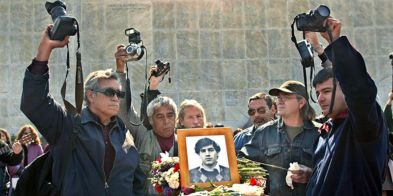 Un gruppo di fotografi durante la cerimonia per il trasferimento dei resti di Rodrigo Rojas, bruciato vivo nel 1986 sotto la dittatura di Pinochet, al Memorial del Detenido Desaparecido di Santiago del Cile, 23 agosto 2003 (VICTOR ROJAS/AFP/Getty Images)