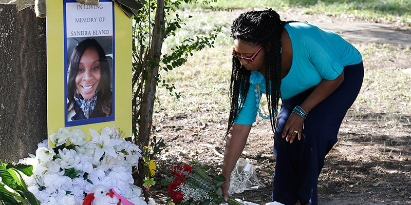 Una donna posa un mazzo di fiori davanti a una fotografia in ricordo di Sandra Bland collocata nei pressi della Prairie View A&M University a Prairie View, in Texas (AP Photo/Pat Sullivan)