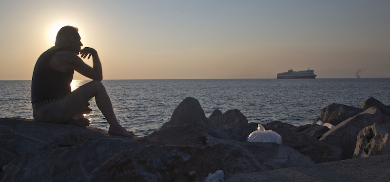 Un migrante sugli scogli del porto di Mitilene, in Grecia (AP Photo/Visar Kryeziu)