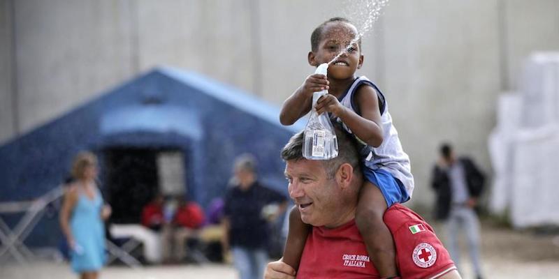 Un volontario della Croce Rossa con un bambino, tra le tende allestite vicino alla stazione Tiburtina, Roma, 20 agosto 2015. 
(Vincenzo Livieri - LaPresse)