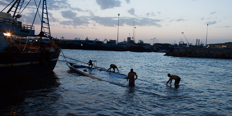 Una barca parzialmente affondata usata dai migranti viene trainata verso il porto di Zuara in Libia (AP Photo/Mohamed Ben Khalifa)