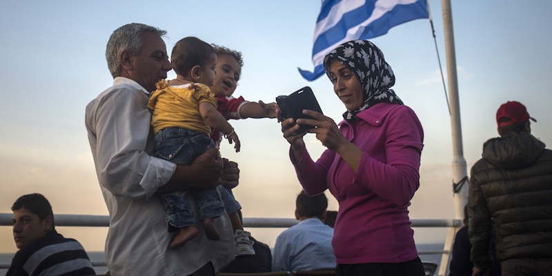 Una famiglia di migranti controlla il cellulare dopo essere salita su una nave greca che dall'isola di Lesbo li condurrà ad Atene, 10 settembre 2015. 
(AP Photo/Santi Palacios)
