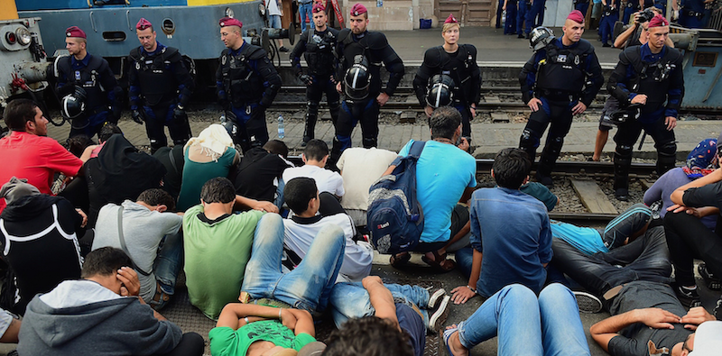 Migranti nella stazione di Bucarest, sorvegliati dalla polizia. (ATTILA KISBENEDEK/AFP/Getty Images)