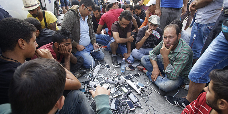 Un gruppo di persone ricarica telefoni cellulari fuori dalla stazione di Budapest, in Ungheria. (Zoltan Balogh/MTI via AP)