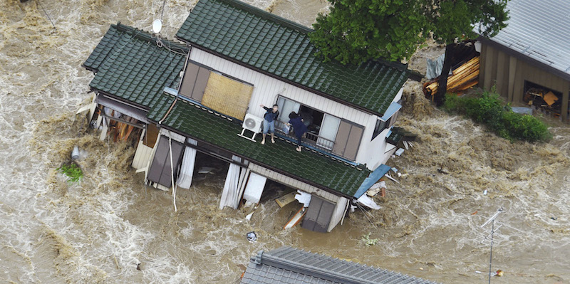 Due persone dentro a una casa alluvionata a Joso, in provincia di Ibaraki, a nordest di Tokyo (Kyodo News via AP)