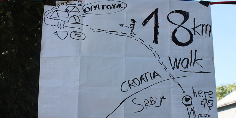 Un cartello scritto a mano indica la lunghezza del percorso per arrivare a Opatovac. (Il Post)